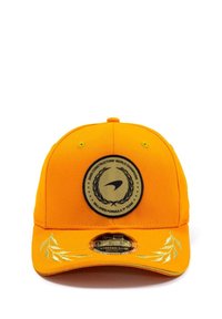 Pomarańczowa czapka z okrągłą czarno-złotą emblematą, z akcentami laurowymi na daszku i zapięciem typu stretch-snap z tyłu.