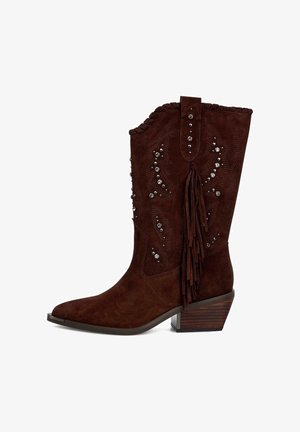 Bottes de cowboy en suède brun avec des franges, des clous en argent décoratifs, un bout pointu et un talon empilé. Des motifs en relief subtils sur la tige.
