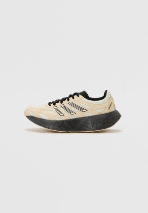 Beżowo-czarny but do biegania Adidas z grubą czarną podeszwą i czarnymi paskami na białym tle.