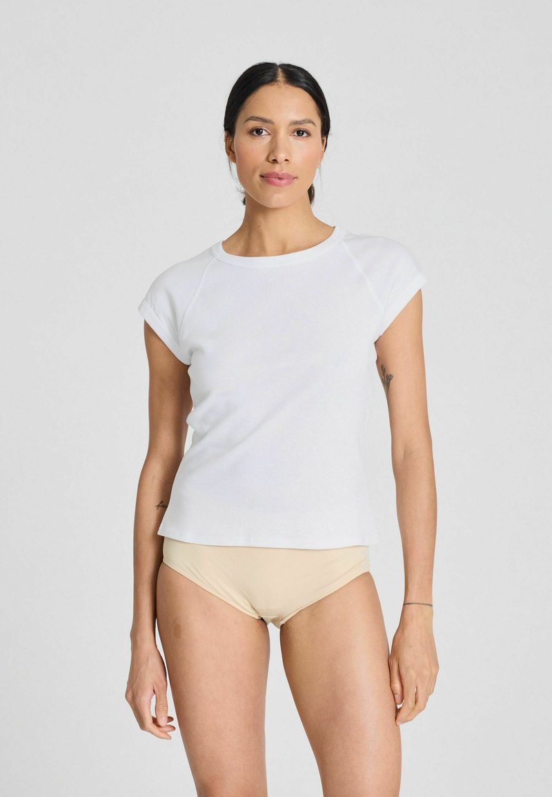 T-shirt bianca a maniche corte con scollatura rotonda e vestibilità rilassata, realizzata in tessuto liscio, abbinata a un sottotono beige chiaro.