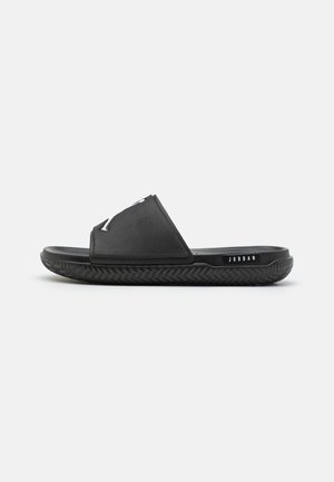 Schwarze Flip-Flops mit einem glatten Oberriemen und einer strukturierten Gummisohle. Mit einem "JORDAN"-Logo an der Seite. Minimalistisches Design und Form.