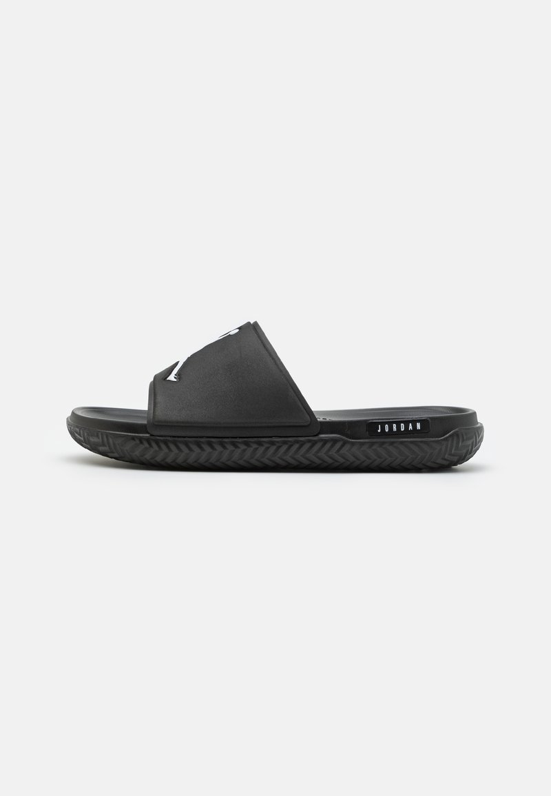 Černé kluzné sandály s hladkým horním popruhem a texturovanou gumovou podrážkou. Na boku se nachází logo "JORDAN". Minimalistický design a tvar.