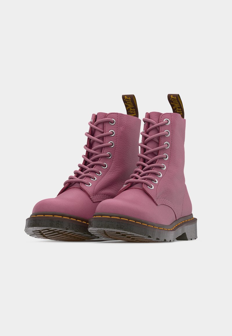 Pair of pink leather lace-up boots with black soles, yellow stitching, and brown pull tabs shown on white background.