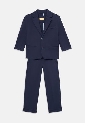 Conjunto de traje infantil en azul marino que incluye una americana con dos botones y bolsillos, acompañado de pantalones a juego, ambos fabricados en un tejido suave.