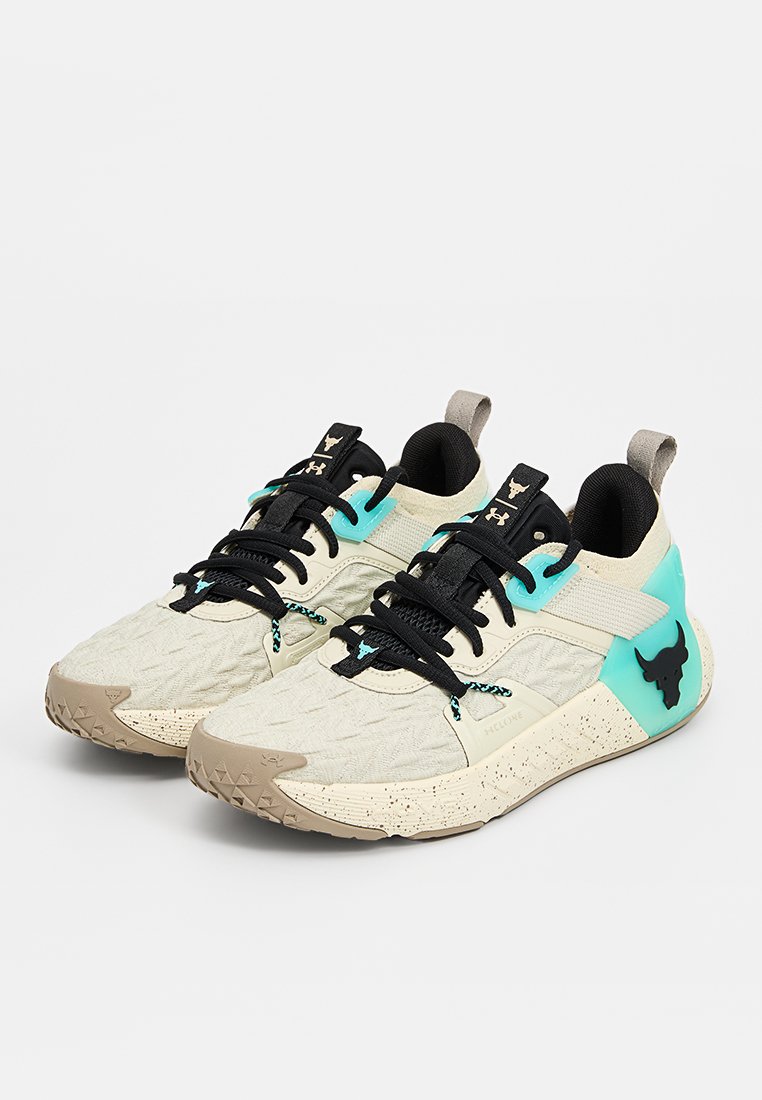 Baskets avec une tige en crème texturée, des lacets noirs, des accents turquoise et un logo de taureau distinctif sur le côté. Semelle en caoutchouc avec un design moucheté.