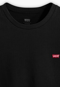 Camiseta negra de algodón con cuello redondo acanalado y un pequeño logotipo bordado de Levi's en rojo en el lado izquierdo del pecho. Textura suave.