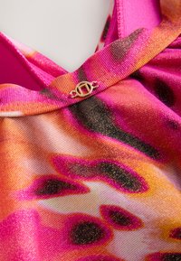 Tissu multicolore dans des tons de rose, orange et noir avec un éclat métallique. Présente un accent de quincaillerie dorée au niveau de l'encolure.