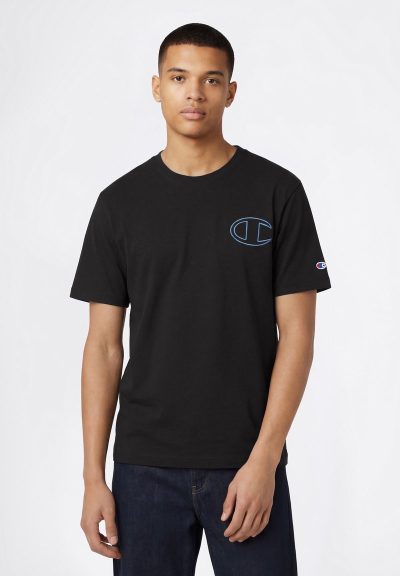 T-shirt en coton noir avec un logo brodé bleu sur la poitrine et un petit patch coloré sur la manche ; col rond, manches courtes.