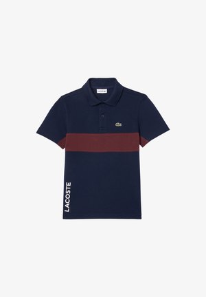 Polo azul marino con una franja horizontal burdeos, logo de Lacoste en el pecho y texto "LACOSTE" en vertical en el lado inferior izquierdo.