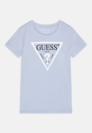 Camiseta de algodón azul claro con un logo triangular en blanco y negro con el texto "GUESS USA WASHED JEANS" en el centro. Mangas cortas, escote redondo.