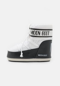 Białe i czarne Moon Boot z sznurówkami, wyściełanym wierzchem i gumową podeszwą, zaprojektowane do użytku w zimnych warunkach i śniegu.