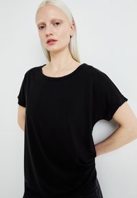 Black short-sleeve T-shirt made of soft fabric, featuring a round neckline and relaxed fit. Simple design with no visible patterns or accents.