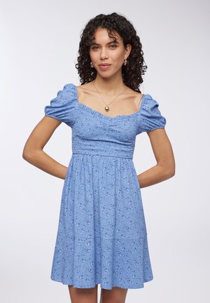 Abito floreale azzurro chiaro con maniche a sbuffo, scollatura quadrata, corpino arricciato e gonna a strati fluente; il tessuto sembra morbido con una delicata texture.