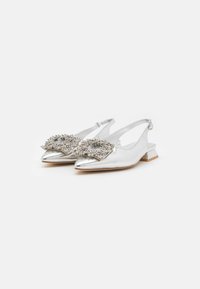 Ballerines argentées à bride arrière avec un bout pointu, un nœud orné d'accents en perles et un petit talon carré. Fini métallique lisse.