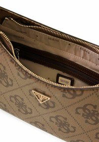 Interno di borsa marrone con motivo a fantasia, dotato di scomparti multipli, dettaglio logo dorato e cerniera testurizzata. Foderato con tessuto beige marchiato "GUESS".