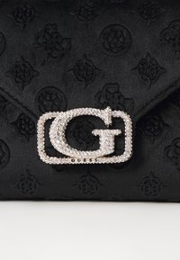 Clutch nera con texture caratterizzata da una prominente fibbia logo in argento decorata con strass, che mette in risalto il suo design elegante.