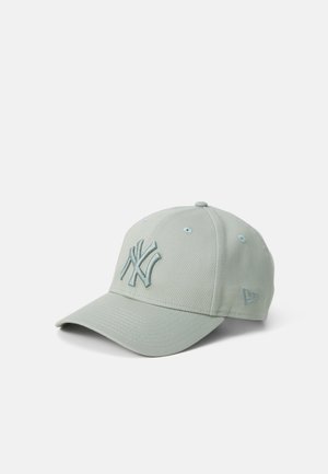 Casquette de baseball gris clair avec le logo des New York Yankees brodé sur le devant et un petit emblème sur le côté.