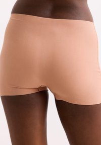 Naadloze, aangesloten shorts in een lichte beige kleur, gemaakt van een gladde, elastische stof, met een brede, elastische tailleband en minimale stiksels.