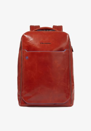 Mochila de cuero roja con una textura suave, que presenta un bolsillo frontal delineado con costura azul y un compartimento principal con doble cremallera.