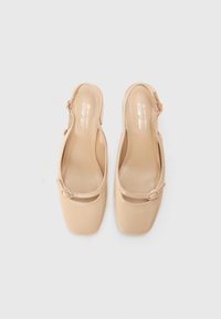 Nudefarbene vegane Slingback-Schuhe mit quadratischen Zehen, einem Riemen mit einem kreisförmigen Akzent und einer glatten, glänzenden Oberfläche.