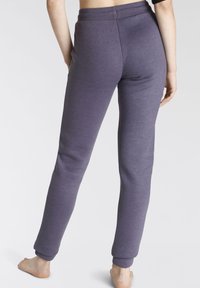 Lila Baumwoll-Sweatpants mit schmaler Passform, elastischem Bund und Bündchen an den Knöcheln. Glatte Textur ohne sichtbare Muster oder Akzente.