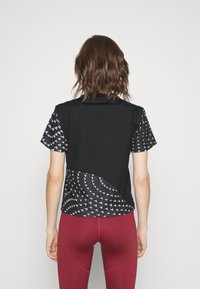 Camiseta deportiva negra y con estampado, de manga corta, diseño curvo y tejido texturizado con acentos de triángulos blancos en la parte trasera.