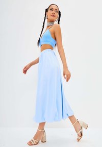 Ensemble deux pièces bleu clair composé d'un haut court à côtes et d'une jupe fluide longueur cheville, complété par des sandales à talons blocs beige à lanières.