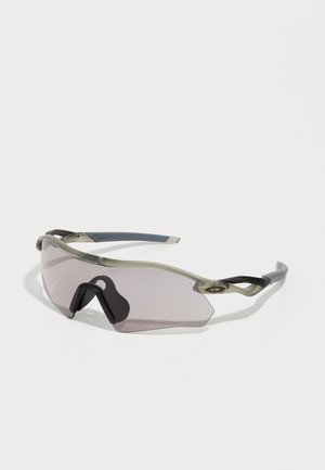 Óculos de sol com uma armação cinza translúcida, lentes com tonalidade e design angular. Apresenta um suporte nasal distinto e hastes em cinza escuro texturizado.