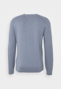 Světle modrý svetr s žebrovanou texturou na rukávech, kulatým výstřihem a přiléhavým střihem. Vyrobený z měkkého materiálu, má bezešvý design na zádech.