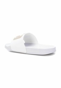 Sandalias deslizantes blancas hechas de material sintético suave. Presentan una cinta ancha con un logotipo beige, suela plana y forma redondeada.