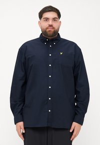 Navy button-up shirt in cotton with long sleeves, a collar, and a single chest pocket featuring a small yellow logo.