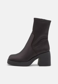 Černé kotníkové boty vyrobené z hladké textilie s robustním podpatkem. Mají štíhlou, přiléhavou holení a detail postranních švů pro elegantní vzhled.