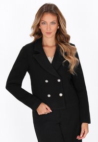 Blazer nero doppiopetto con texture simile alla seta, revers a punta e dettagli con bottoni argentati. Stile aderente, taglio corto, design elegante.