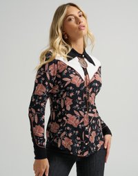 Langermet bluse med svart blomsterdesign på mørk bakgrunn, kontrasterende hvit yoke og dekorativ knappelukking.