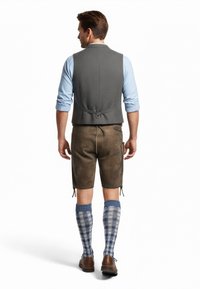 Gilet grigio su una camicia azzurro chiaro, pantaloni corti in pelle marrone e calze lunghe a quadri blu e bianchi. Le scarpe marroni completano l'outfit.