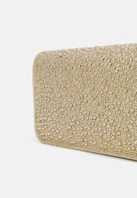 Guldig kuvertväska med texturerad yta prydd med små runda pärlor, rektangulär form och en slät metallisk kant runt kanterna.