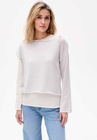 Helles graues, langärmliges Oberteil mit rundem Ausschnitt und offenen Schulterdetails. Weiche Textur mit einem schichtartigen Look und kontrastrendem Saum.