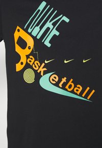 Camisa negra con texto y formas abstractas multicolores que dicen "Nike Basketball", con turquesa, naranja, amarillo y pequeños logotipos de raya de Nike.