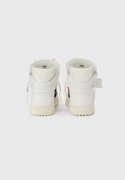 Αθλητικά παπούτσια ψηλού τύπου σε λευκό χρώμα με μαύρες λεπτομέρειες, δέρμα με υφή και χοντρή σόλα. Διαθέτουν πορτοκαλί θηλιές για τράβηγμα και φερμουάρ στα πλευρά.