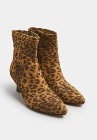 Botas de tobillo de estampado de leopardo hechas de suave gamuza, con puntera puntiaguda y un bajo tacón cuadrado. Presentan un interior negro y costuras en contraste.