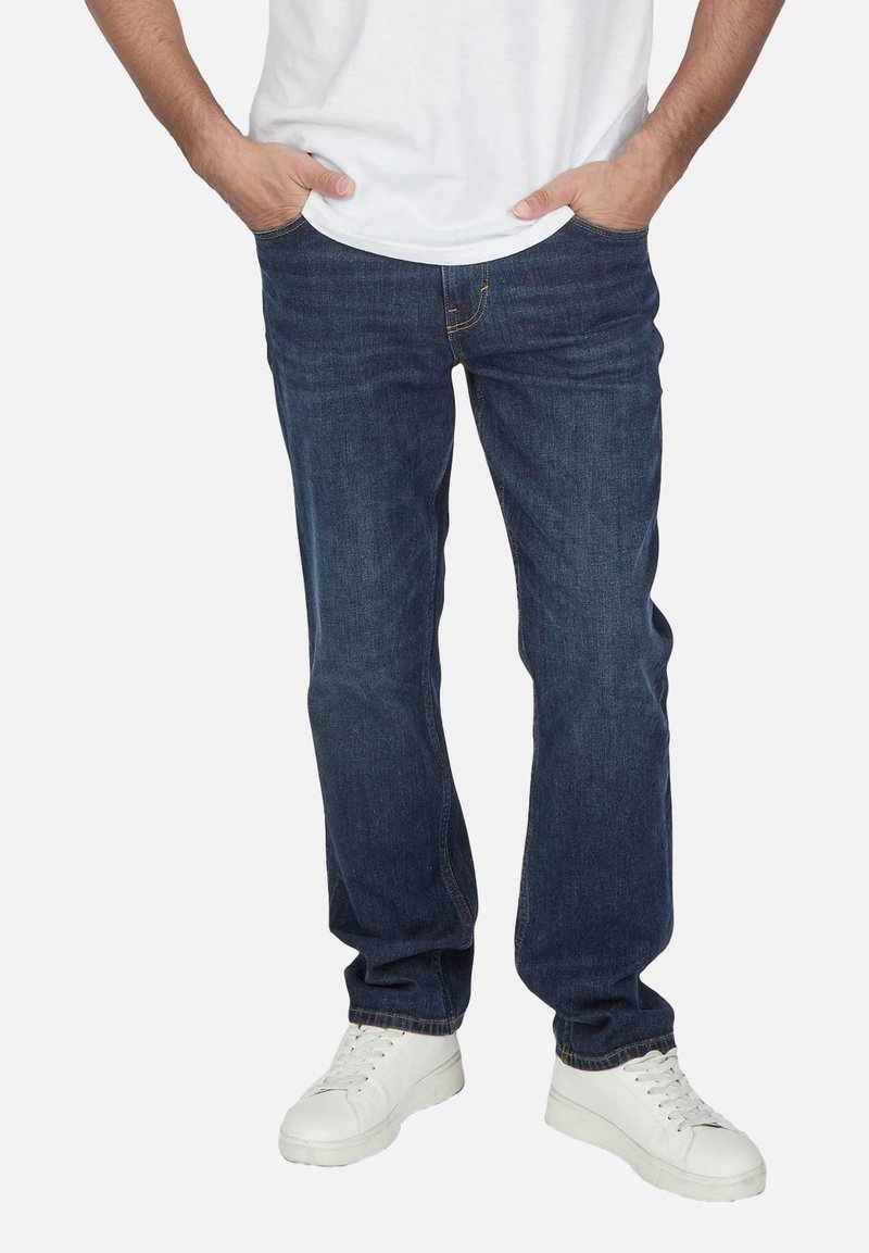 Dunkelblaue Denim-Jeans mit lockerer Passform, klassischem Fünf-Taschen-Design und weißen Turnschuhen. Glatter Stoff mit einem sauberen Look.