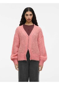 Cardigan rosa chiaro realizzato in un materiale morbido e testurizzato. Presenta un profondo scollo a V, maniche oversize e un design frontale senza bottoni.