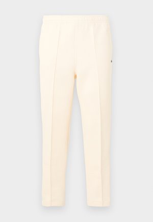 Κρεμ παντελόνι με ίσια γραμμή, ελαστική μέση και σχεδιασμό με πιέτες μπροστά, παρουσιασμένο σε απλό φόντο.