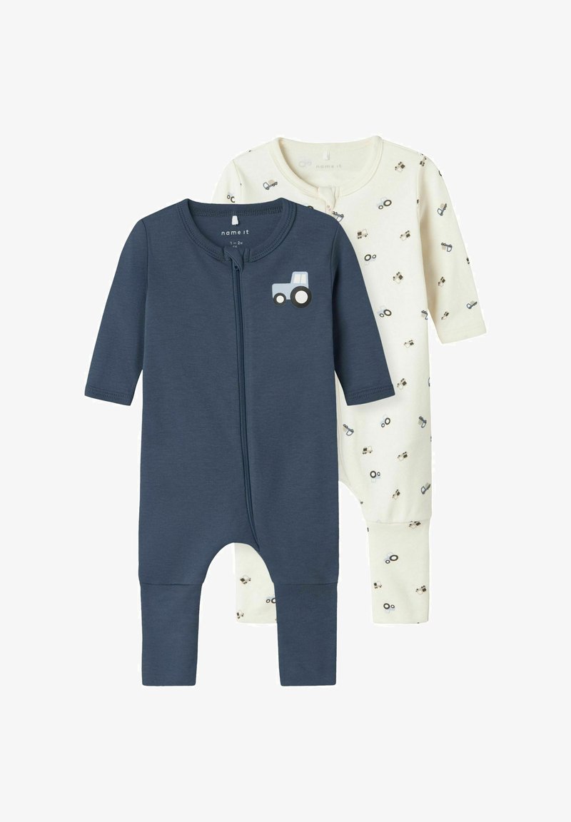 Two long-sleeved baby rompers: one in dark blue with a tractor print, the other in cream with a tractor pattern. Made of soft cotton.