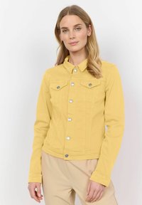 Gul denimjacka med krage, två bröstfickor, silverknappar och långa ärmar. Slät textur och figursydd design.