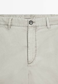 Hellgraue Hose mit Knopfverschluss, Fronttaschen und glatter Baumwollstoffoberfläche. Einfaches Design mit minimalen Nähdetails.