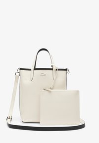 Sac cabas en cuir blanc avec des accents et des poignées noires. Comprend une pochette détachable assortie. Surface texturée, design minimaliste.