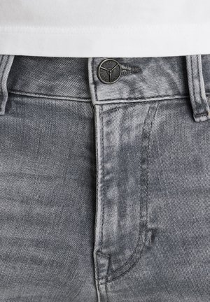 Šedé džíny z denimu s texturovaným povrchem, vybavené černým kovovým knoflíkem a kontrastním bílým prošíváním podél pásu a kapes.