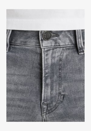 Szare dżinsy z teksturowanym wykończeniem, z czarnym metalowym guzikiem i kontrastowym białym przeszyciem wzdłuż pasa i kieszeni.