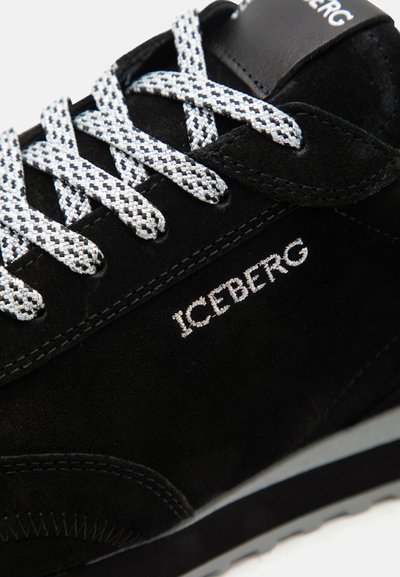 Μαύρο σουεντ αθλητικό παπούτσι με άσπρα και μαύρα κορδόνια με μοτίβο, κεντημένο όνομα μάρκας "ICEBERG" στο πλάι και ορατή γλώσσα με λογότυπο.